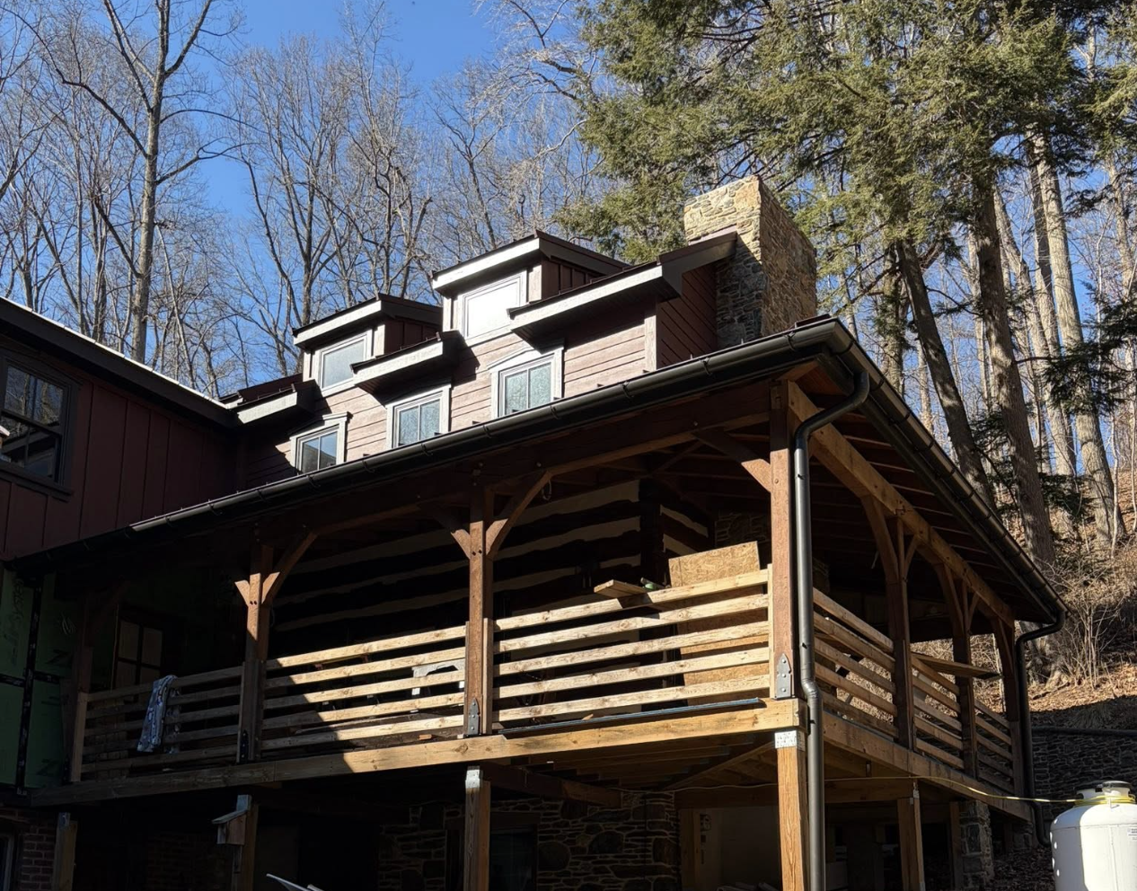 Freshly installed seamless gutters and downspouts on a timber-frame home